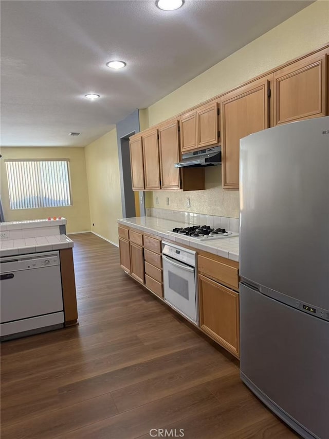 12673 Field Way, Victorville, CA 92395 - kitchen with white appliances, tile counters, under cabinet range hood, dark wood-style flooring, and backsplash
