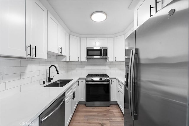 9525 Sylmar Ave Unit 2, Panorama City, CA 91402 - kitchen with appliances with stainless steel finishes, white cabinetry, light countertops, tasteful backsplash, and wood finished floors