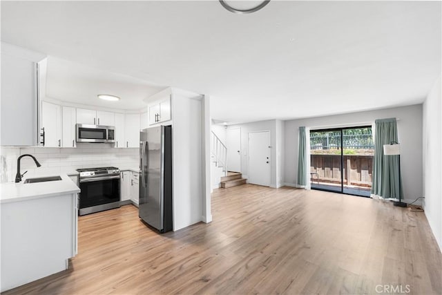 9525 Sylmar Ave Unit 2, Panorama City, CA 91402 - kitchen with stainless steel appliances, light wood finished floors, light countertops, backsplash, and white cabinetry