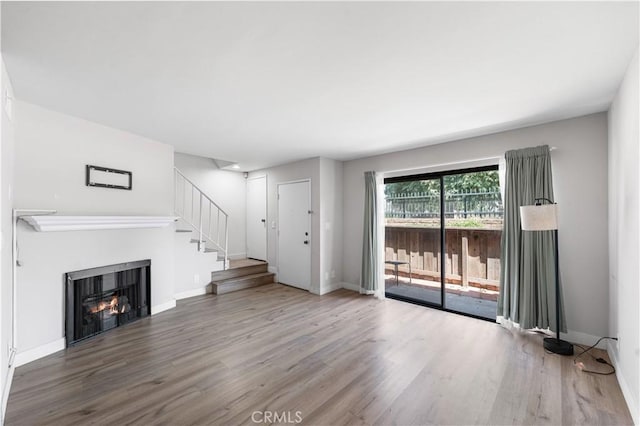 9525 Sylmar Ave Unit 2, Panorama City, CA 91402 - unfurnished living room featuring wood finished floors, a lit fireplace, and stairway