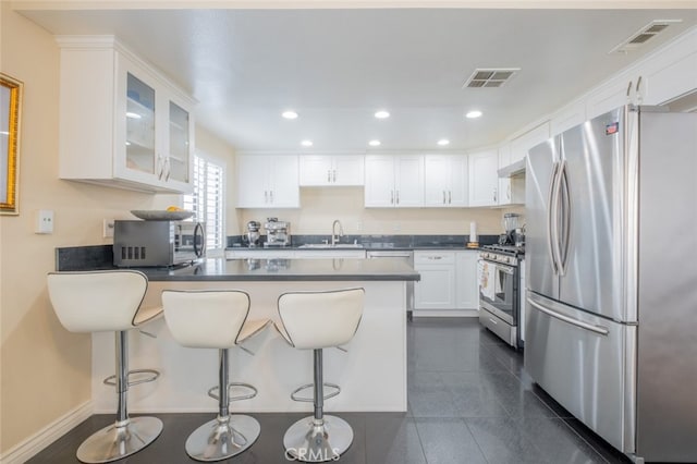 15053 Sherman Way Unit A, Van Nuys, CA 91405 - kitchen featuring stainless steel appliances, a peninsula, dark countertops, glass insert cabinets, and white cabinets