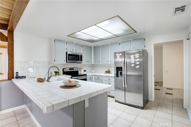 27218 Monk St, Menifee, CA 92586 - kitchen with stainless steel appliances, a peninsula, light tile patterned floors, tile counters, and backsplash