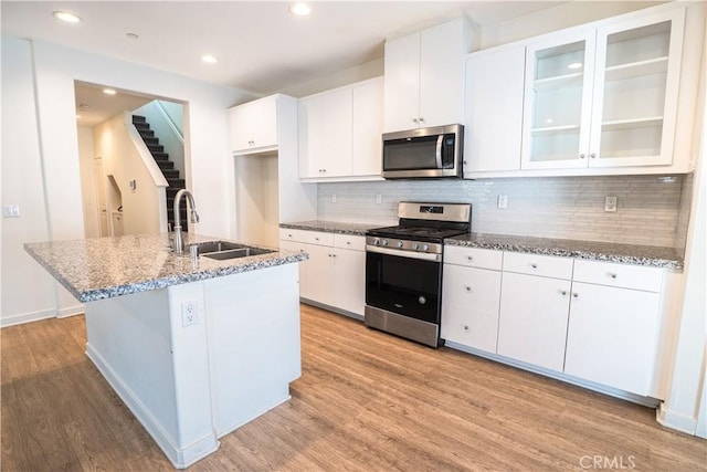 12893 Breccia Way, Moreno Valley, CA 92555 - kitchen featuring appliances with stainless steel finishes, light wood finished floors, tasteful backsplash, light stone counters, and recessed lighting