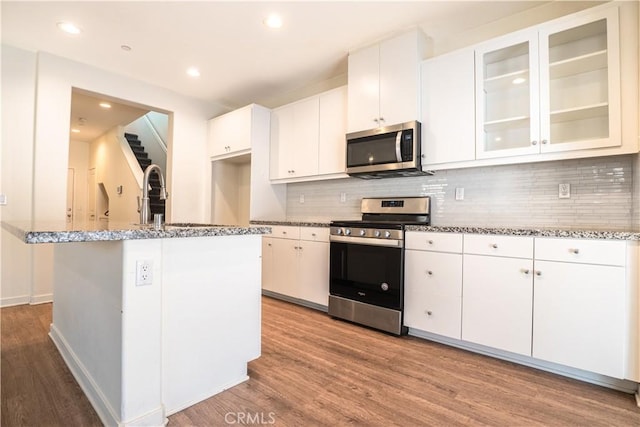 12893 Breccia Way, Moreno Valley, CA 92555 - kitchen featuring appliances with stainless steel finishes, wood finished floors, backsplash, white cabinets, and recessed lighting