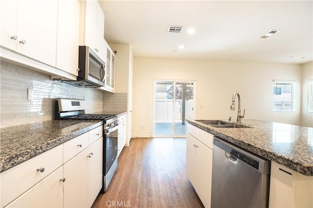12893 Breccia Way, Moreno Valley, CA 92555 - kitchen featuring stainless steel appliances, wood finished floors, white cabinets, tasteful backsplash, and dark stone counters