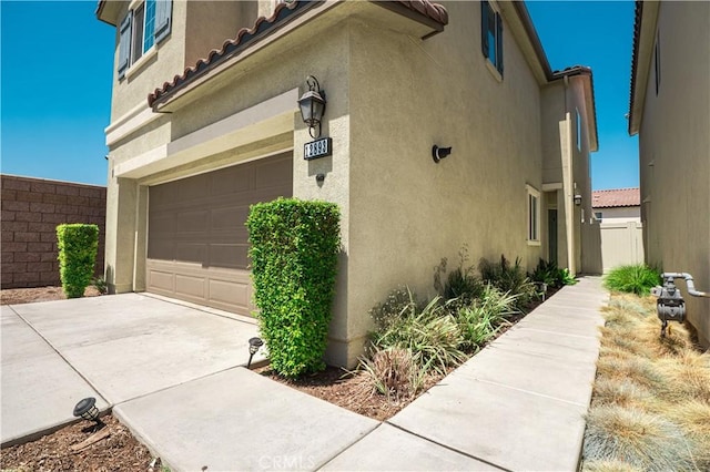12893 Breccia Way, Moreno Valley, CA 92555 - view of side of property featuring stucco siding, an attached garage, driveway, and a tile roof