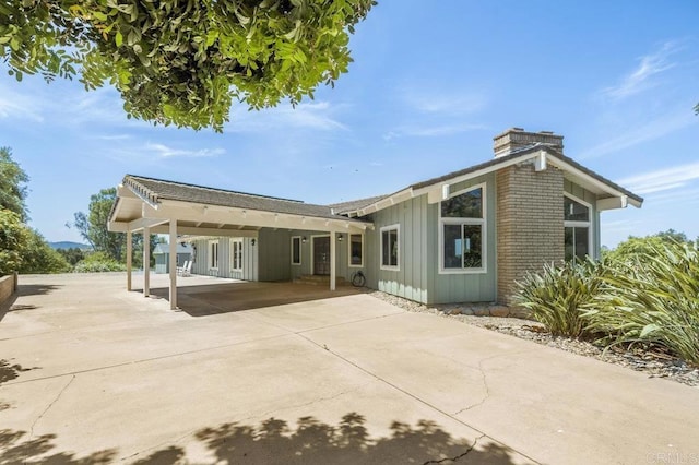 15935 Mac Tan Ln, Valley Center, CA 92082 - rear view of house featuring board and batten siding, a chimney, driveway, and an attached carport
