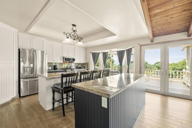 15935 Mac Tan Ln, Valley Center, CA 92082 - kitchen featuring stainless steel appliances, an island with sink, a raised ceiling, and light wood-style flooring