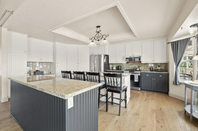 15935 Mac Tan Ln, Valley Center, CA 92082 - kitchen with appliances with stainless steel finishes, a raised ceiling, a kitchen island, white cabinetry, and crown molding