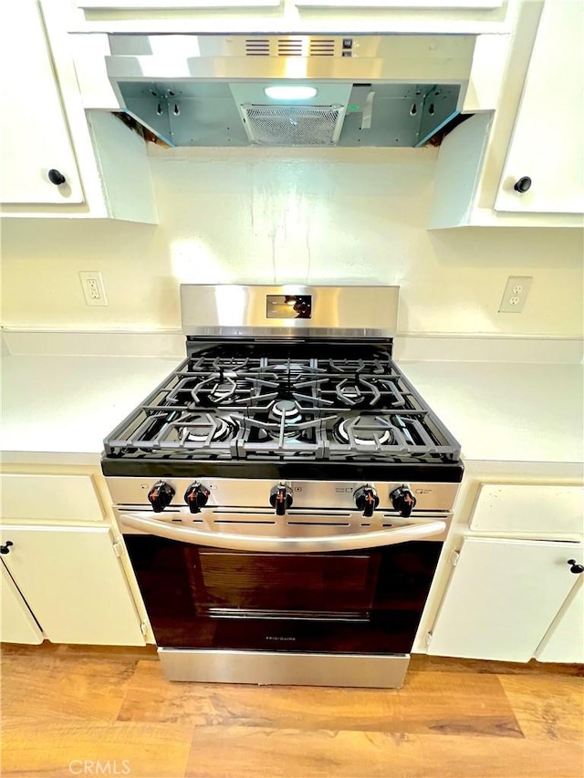 13895 Parkway Dr Unit 79, Garden Grove, CA 92843 - kitchen with stainless steel gas stove, exhaust hood, white cabinetry, and light countertops