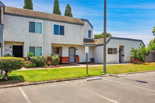 13895 Parkway Dr Unit 79, Garden Grove, CA 92843 - view of front of home with uncovered parking, stucco siding, and a front lawn