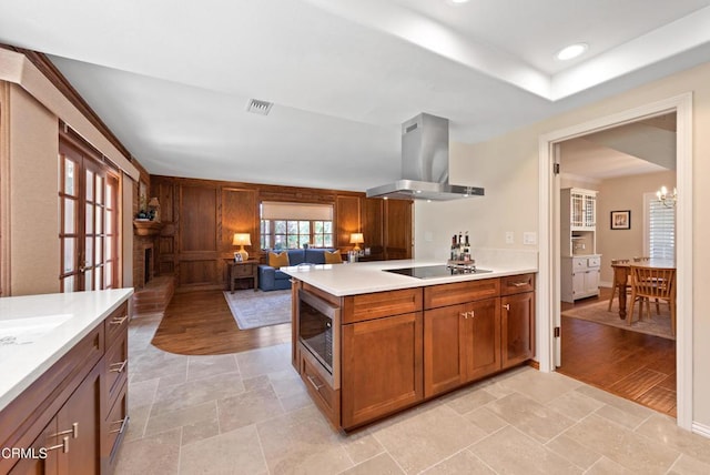 2274 Via Tomas, Camarillo, CA 93010 - kitchen with ventilation hood, stainless steel microwave, black electric stovetop, light countertops, and brown cabinetry