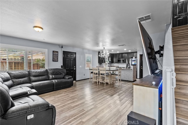 26120 Goldman Pl, Saugus, CA 91350 - living room featuring a chandelier, light wood-type flooring, and stairs