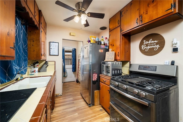 950 E Yale St, Ontario, CA 91764 - kitchen with appliances with stainless steel finishes, tile counters, light wood-style flooring, and brown cabinets