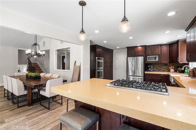 11212 Brunswick Way N, Tustin, CA 92705 - kitchen featuring stainless steel appliances, light wood-style flooring, light countertops, a kitchen breakfast bar, and recessed lighting