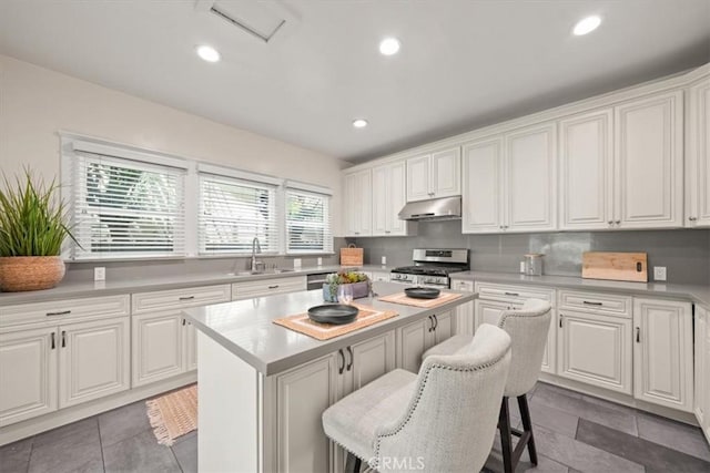 268 S Norton Ave, Los Angeles, CA 90004 - kitchen featuring stainless steel appliances, under cabinet range hood, a kitchen island, a kitchen bar, and white cabinetry