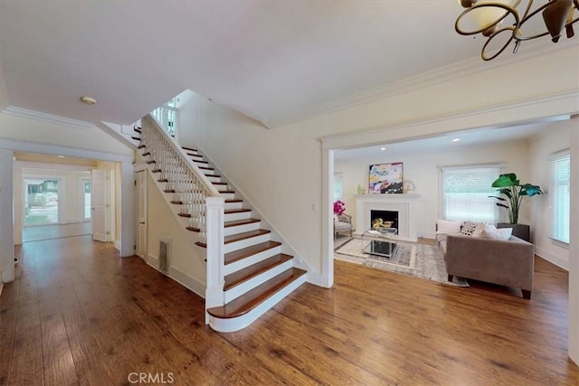 268 S Norton Ave, Los Angeles, CA 90004 - stairs with wood finished floors, crown molding, a fireplace with raised hearth, and a chandelier