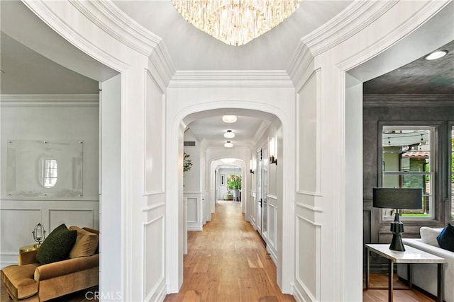 7 Kent Ct, Ladera Ranch, CA 92694 - hall featuring a decorative wall, arched walkways, light wood finished floors, a chandelier, and crown molding