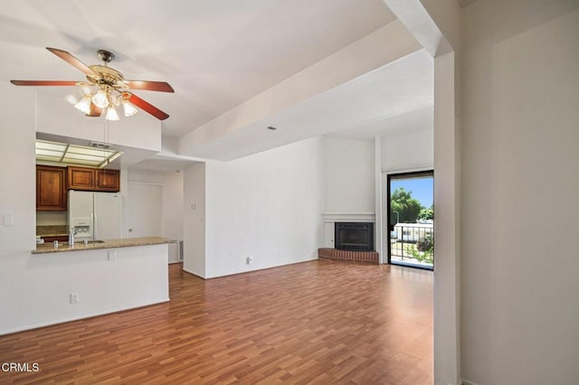 7211 Cozycroft Ave Unit 40, Winnetka, CA 91306 - unfurnished living room featuring ceiling fan, wood finished floors, and a fireplace with raised hearth
