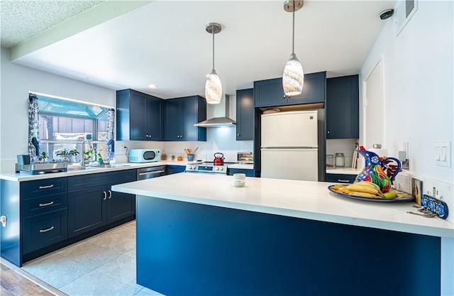 9739 Reseda Blvd Unit 36, Northridge, CA 91324 - kitchen featuring stainless steel appliances, a peninsula, wall chimney range hood, light countertops, and hanging light fixtures
