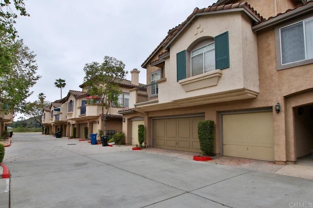 11368 Via Rancho San Diego Unit C, El Cajon, CA 92019 - view of front of property featuring an attached garage, stucco siding, a tiled roof, and driveway