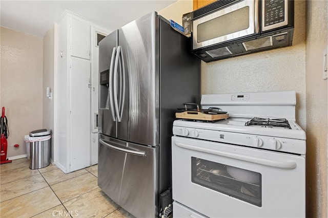 1445 W 155th St, Compton, CA 90220 - kitchen with appliances with stainless steel finishes, light tile patterned floors, and white cabinets