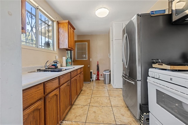 1445 W 155th St, Compton, CA 90220 - kitchen featuring white stove, brown cabinetry, light countertops, and light tile patterned flooring