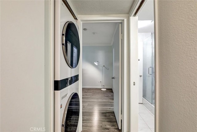 550 Orange Ave Unit 212, Long Beach, CA 90802 - washroom featuring stacked washing machine and dryer, crown molding, wood finished floors, and a textured wall