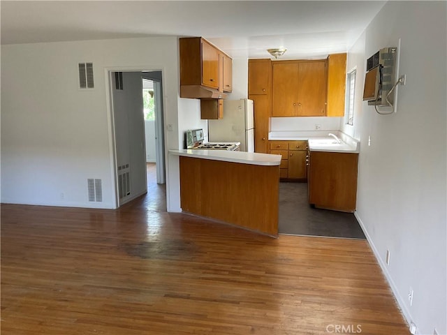 6259 Coldwater Canyon Ave Unit 13, North Hollywood, CA 91606 - kitchen with under cabinet range hood, stove, light countertops, brown cabinetry, and dark wood-type flooring
