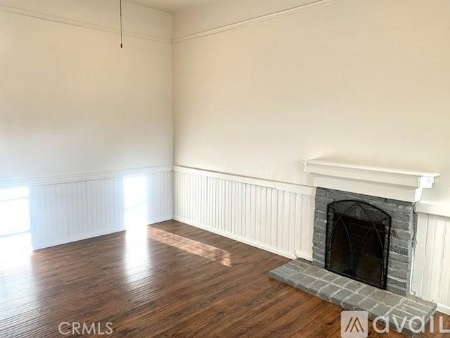 340 E Main St, San Jacinto, CA 92583 - unfurnished living room featuring a fireplace, wood finished floors, and a wainscoted wall