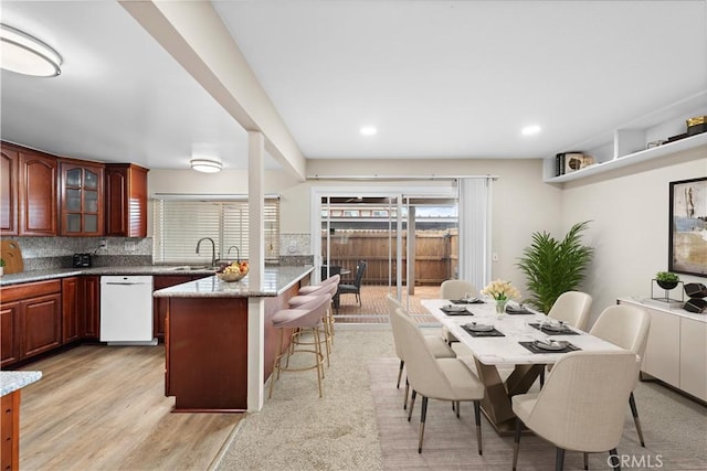 4690 Larwin Ave, Cypress, CA 90630 - kitchen with white dishwasher, a kitchen bar, a peninsula, glass insert cabinets, and tasteful backsplash