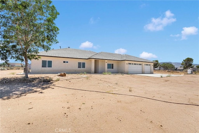 6643 Avenal St, Phelan, CA 92371 - view of front of home with an attached garage, dirt driveway, and stucco siding