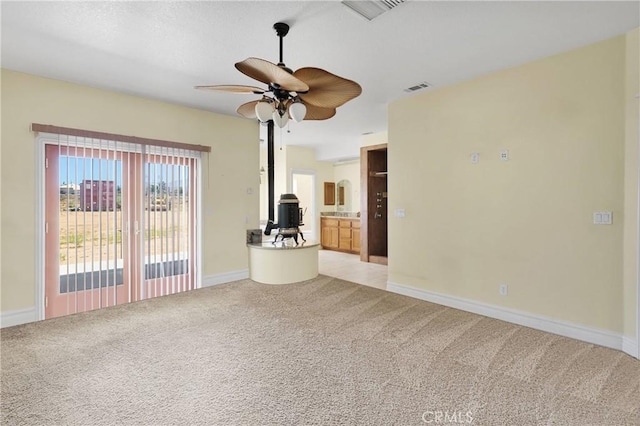 6643 Avenal St, Phelan, CA 92371 - unfurnished living room with light colored carpet, a ceiling fan, and a wood stove