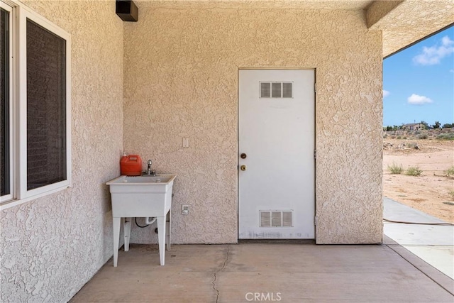 6643 Avenal St, Phelan, CA 92371 - doorway to property with stucco siding and a patio area