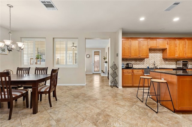30355 Lamplighter Ln, Menifee, CA 92584 - kitchen with a chandelier, dark countertops, tasteful backsplash, brown cabinets, and recessed lighting