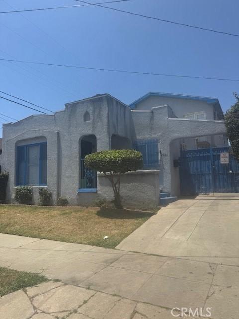 8463 S Halldale Ave, Los Angeles, CA 90047 - view of front facade with stucco siding, driveway, and a gate