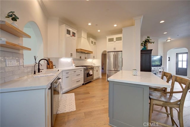 1910 Fixlini St, San Luis Obispo, CA 93401 - kitchen featuring stainless steel appliances, custom range hood, arched walkways, open shelves, and a kitchen island