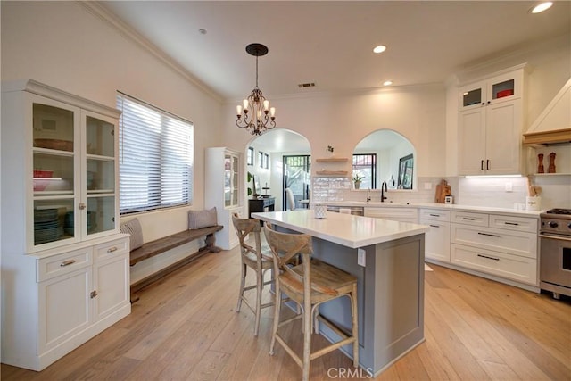 1910 Fixlini St, San Luis Obispo, CA 93401 - kitchen with open shelves, stainless steel range, white cabinetry, a breakfast bar, and crown molding