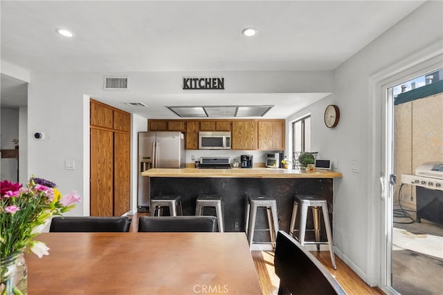 15230 Roxford St Unit 61, Sylmar, CA 91342 - kitchen with appliances with stainless steel finishes, a peninsula, brown cabinets, light countertops, and a kitchen bar
