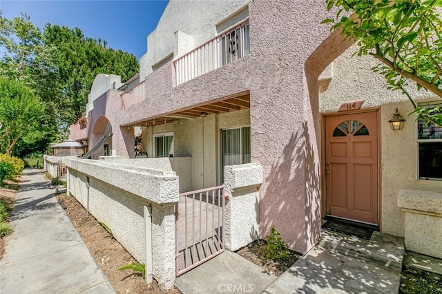 12411 Osborne St Unit 114, Pacoima, CA 91331 - view of exterior entry featuring stucco siding and a balcony