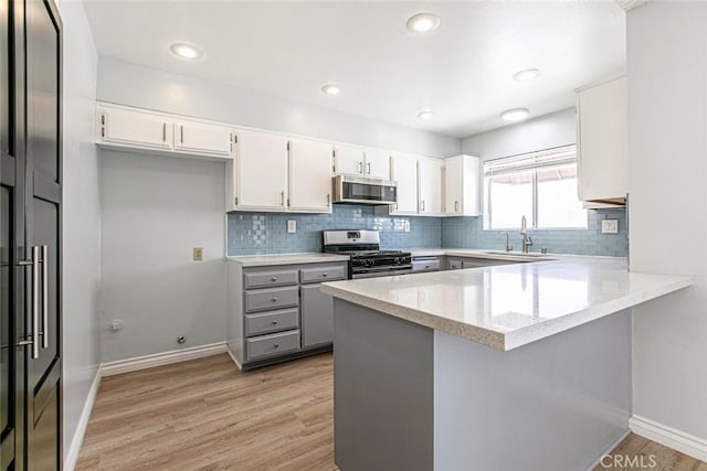 12411 Osborne St Unit 114, Pacoima, CA 91331 - kitchen with appliances with stainless steel finishes, a peninsula, light wood-type flooring, backsplash, and recessed lighting