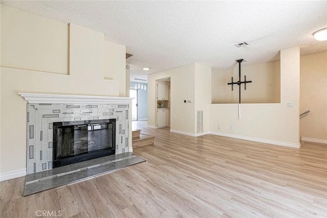 12411 Osborne St Unit 114, Pacoima, CA 91331 - unfurnished living room with wood finished floors, a textured ceiling, and a stone fireplace