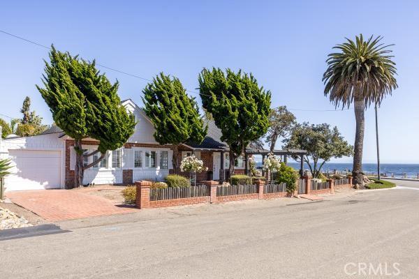 1780 Ocean Blvd, Pismo Beach, CA 93449 - view of property hidden behind natural elements with a fenced front yard, a garage, and a water view
