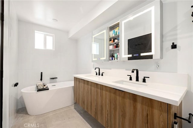 922 N Ridgewood Pl, Los Angeles, CA 90038 - bathroom featuring a freestanding bath, double vanity, tile patterned flooring, and tile walls