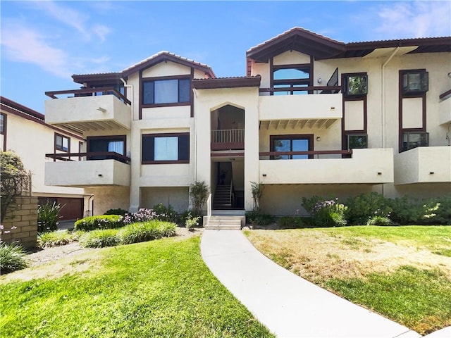 28021 Sarabande Ln Unit 1209, Canyon Country, CA 91387 - view of front of home featuring stucco siding, a balcony, and a front yard