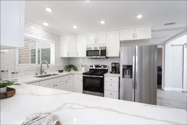 2358 Via Mariposa E Unit B, Laguna Woods, CA 92637 - kitchen with appliances with stainless steel finishes, backsplash, white cabinetry, light stone counters, and light wood-style floors