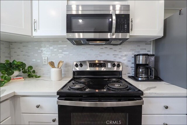 2358 Via Mariposa E Unit B, Laguna Woods, CA 92637 - kitchen featuring appliances with stainless steel finishes, white cabinets, decorative backsplash, and light stone counters