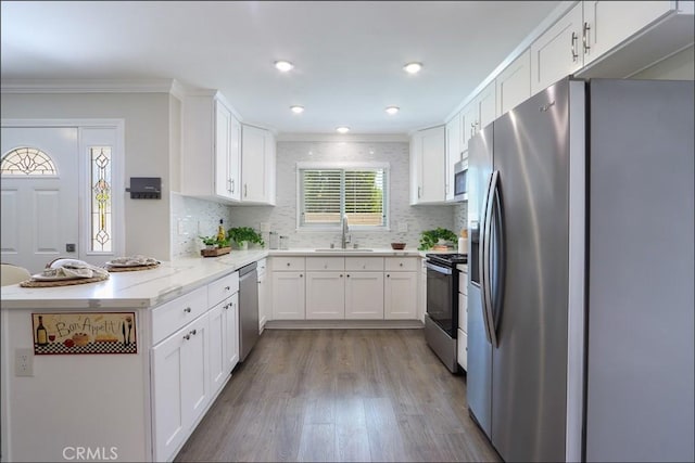 2358 Via Mariposa E Unit B, Laguna Woods, CA 92637 - kitchen with stainless steel appliances, a peninsula, ornamental molding, wood finished floors, and white cabinets