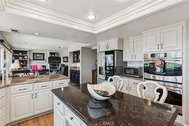 27201 Via Aurora, Mission Viejo, CA 92691 - kitchen with appliances with stainless steel finishes, crown molding, white cabinetry, open floor plan, and dark stone countertops