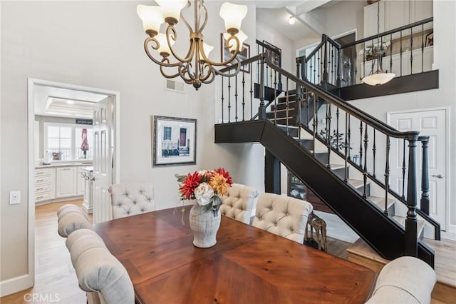 27201 Via Aurora, Mission Viejo, CA 92691 - dining area with a chandelier, a towering ceiling, stairway, light wood finished floors, and beamed ceiling